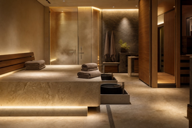 Calm stone thermal recovery room with warm indirect lighting and folded towels